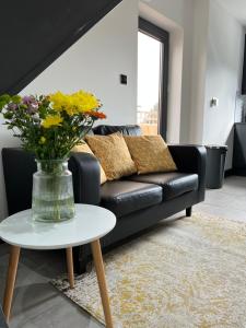 a black couch with a vase of flowers on a table at The Crouch - Apartment 2 in Grays Thurrock