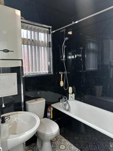 La salle de bains est pourvue d'une baignoire blanche, de toilettes et d'un lavabo. dans l'établissement Le Crescent Lodge, Room Stay , Middlesbrough City, à Middlesbrough