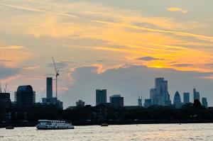 a boat on the water in front of a city at Riverside Premium En suite Double Room E14 in London