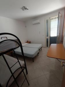 a small room with two beds and a table at Stanze villa Morosini in Torre San Giovanni Ugento