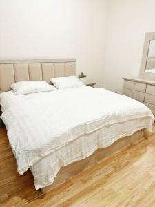 a bedroom with a white bed and a wooden floor at 2 Bedroom Apartment 2BB in Riyadh