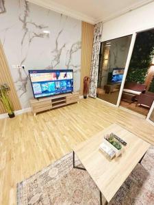 a living room with a large television and a table at شقة جميلة بغرفتين نوم ومدخل خاص 2BB in Riyadh