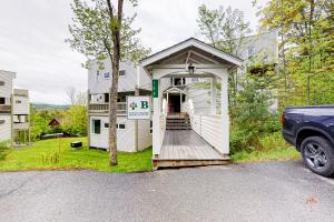 a white house with a porch and a driveway at Mountainside Resort B202 in Stowe
