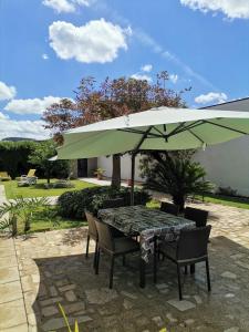una mesa y sillas con una sombrilla verde en Casa Além Rio - quartos para 6 hóspedes em Santo Tirso en Santo Tirso