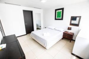 a white bedroom with a bed and a night stand at 1206 Increible suite en Puerto santa Ana in Guayaquil