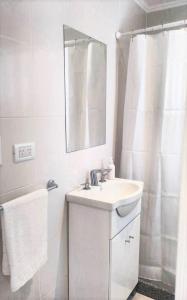Baño blanco con lavabo y espejo en Sierras de Tandil Departamentos en Tandil