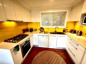 uma cozinha com armários brancos e um forno com placa de fogão em The Treehouse at Copa em Copacabana