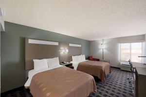 a hotel room with two beds and a desk at Quality Inn & Suites DFW Airport South in Irving