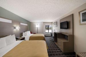 a hotel room with two beds and a flat screen tv at Quality Inn & Suites DFW Airport South in Irving