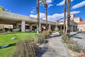 a building with palm trees and a sidewalk at Beautiful Palm Desert Townhome with Community Perks! in Palm Desert