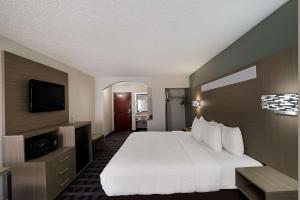 a hotel room with a bed and a flat screen tv at Quality Inn & Suites Irving DFW Airport South in Irving