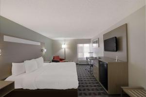 a hotel room with a bed and a flat screen tv at Quality Inn & Suites Irving DFW Airport South in Irving