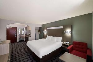a hotel room with a bed and a red chair at Quality Inn & Suites Irving DFW Airport South in Irving