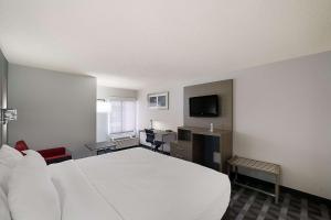 a hotel room with a white bed and a desk at Quality Inn & Suites Irving DFW Airport South in Irving