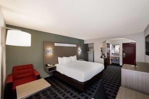 a hotel room with a bed and a red chair at Quality Inn & Suites Irving DFW Airport South in Irving