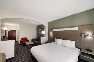 a hotel room with a large white bed and a chair at Quality Inn & Suites Irving DFW Airport South in Irving