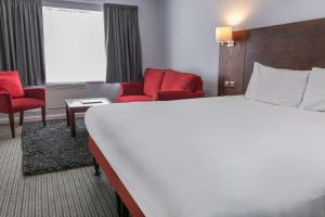 a hotel room with a bed and two red chairs at The Stuart Hotel, Sure Hotel Collection by Best Western in Derby