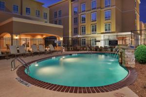 a pool at a hotel with chairs and a building at Homewood Suites Odessa in Odessa