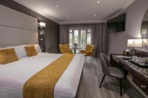 una camera d'albergo con un grande letto e una scrivania di Best Western Premier Heronston Hotel & Spa a Bridgend