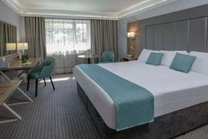 ブリジェンドにあるBest Western Premier Heronston Hotel & Spaの大きなベッドとデスクが備わるホテルルームです。