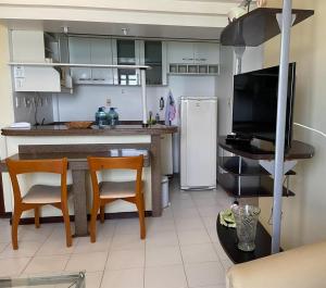 a kitchen with a table and two chairs and a television at Flat no Pituba Sol 302 E 311 in Salvador