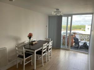 a dining room with a table and chairs and a balcony at Newquay Fistral Beach View in Newquay