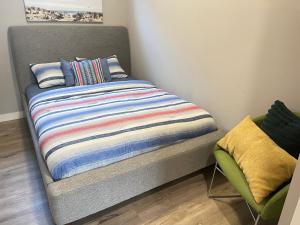 uma cama com um cobertor listrado e uma cadeira em Cozy basement suite em Calgary