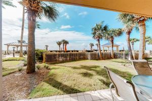 a patio with a table and chairs and palm trees at The Beach Club Resort and Spa II in Gulf Shores