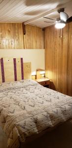 1 dormitorio con 1 cama y pared de madera en Llahuar Lodge, en Cabanaconde