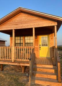 a cabin with a yellow door on a deck at Yellow Rose Cabin in Hye