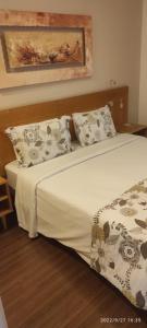 1 dormitorio con 1 cama con sábanas y almohadas blancas en Apart Hotel 48, en Mogi das Cruzes