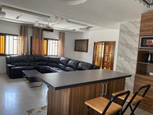 ein Wohnzimmer mit einem schwarzen Ledersofa und einer Bar in der Unterkunft Villa OMARI Situé à Saly Portudal Villa 2 Chambres bien équipés proche de tout in Saly Portudal
