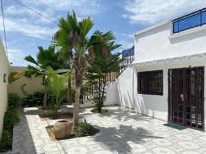 ein weißes Haus mit Palmen im Innenhof in der Unterkunft Villa OMARI Situé à Saly Portudal Villa 2 Chambres bien équipés proche de tout in Saly Portudal