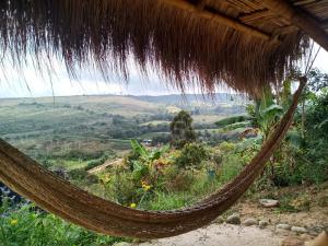 a hammock hanging from a thatch hut with a view at Casa Ecológica Madre Tierra in Curití