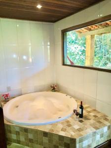 a large bath tub in a bathroom with a window at Pousada Bella Ana in Visconde De Maua