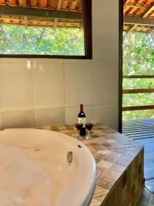 una vasca da bagno con una bottiglia di vino e due bicchieri di Pousada Bella Ana a Visconde De Maua