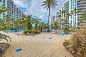 un patio con palmeras, mesas y edificios en Palms of Destin 21211, en Destin