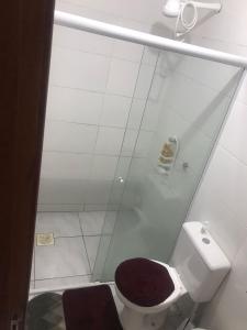 een witte badkamer met een toilet met een bruine stoel bij casa palhoça in Palhoça