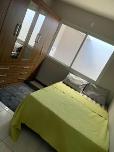 een slaapkamer met een groen bed en een groot raam bij casa palhoça in Palhoça