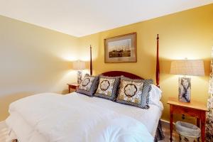 a bedroom with a white bed with two lamps at Village Green Unit 14E in Stowe +34 photos