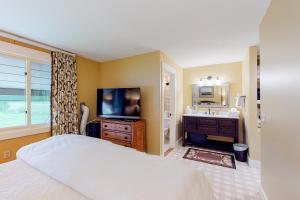a bedroom with a bed and a television and a sink at Village Green Unit 14E in Stowe