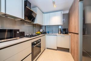 una cocina con armarios blancos y electrodomésticos de acero inoxidable en Casamax Suites, en Antalya