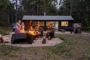 a group of people sitting around a fire in front of a cabin at Gleneagle Tasmania in Riana