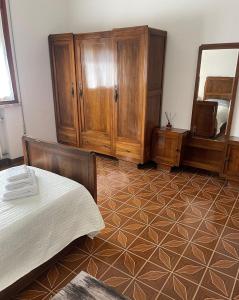 1 dormitorio con cama, armarios de madera y espejo en Le ballerine, en Crocetta