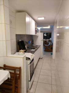 een keuken met witte kasten en een fornuis bij Apartamento pé na areia e piscina in Capão da Canoa