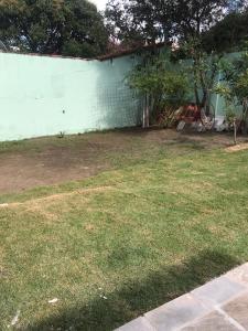 a yard with a white wall and some grass at CASA GRIEBELER 02 in Cabo Frio