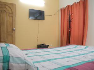 a bedroom with a bed with a tv on the wall at Golpata Bed & Breakfast in Dhaka