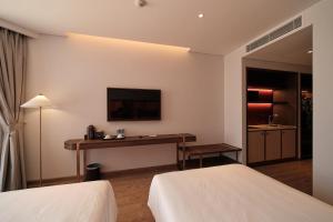 ファンティエットにあるCondotel S1007 Apec Mandala Mũi Néのベッド2台とデスクが備わるホテルルームです。
