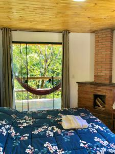 a bedroom with a bed and a large window at Pousada Bella Ana in Visconde De Maua