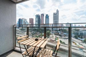 uma varanda com um banco de madeira e vista para a cidade em Summer Suites KLCC Apartments by soulasia em Kuala Lumpur